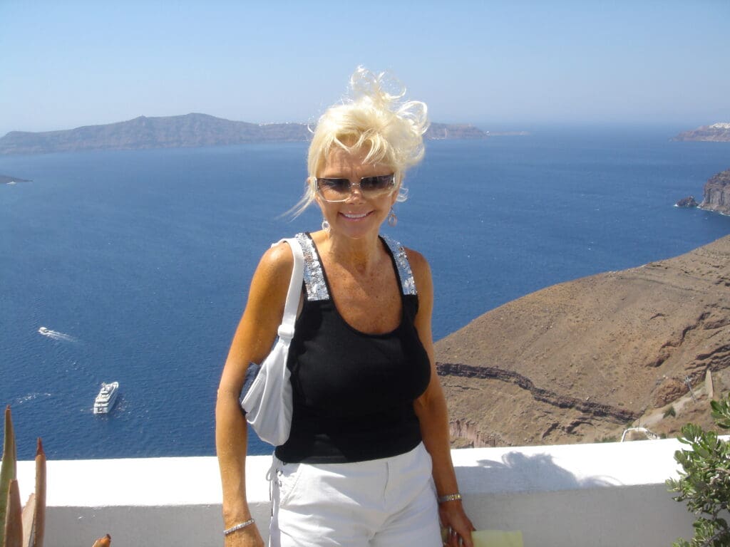 A woman standing on the side of a building near the ocean.