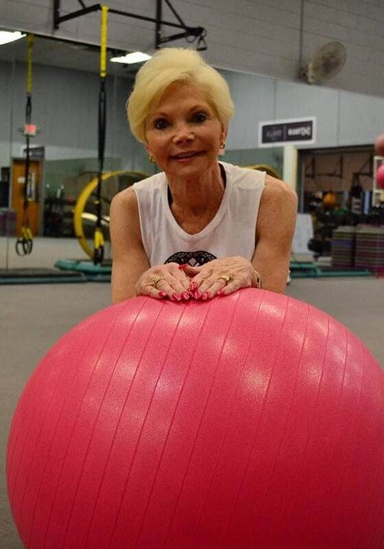 A woman is posing with an exercise ball.