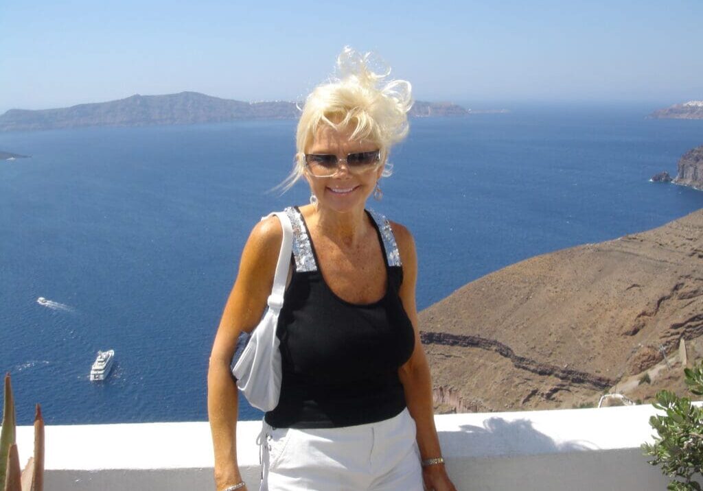 A woman standing on the side of a building near the ocean.