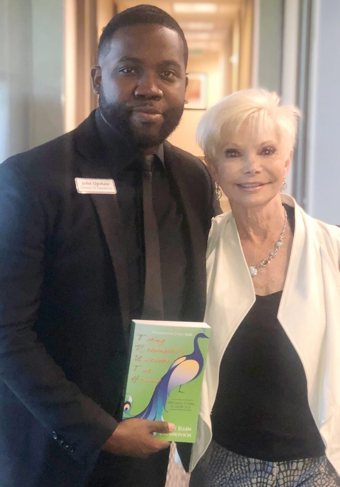 A man and woman posing for the camera holding a book.